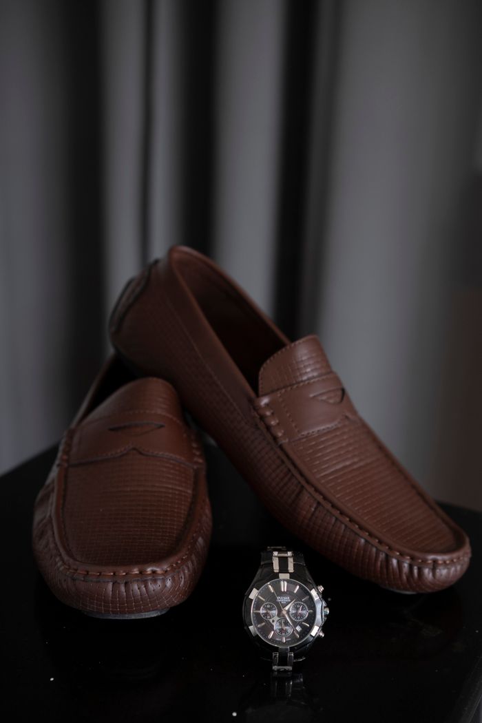 Sophisticated brown leather loafers paired with a classic wristwatch for a stylish presentation.